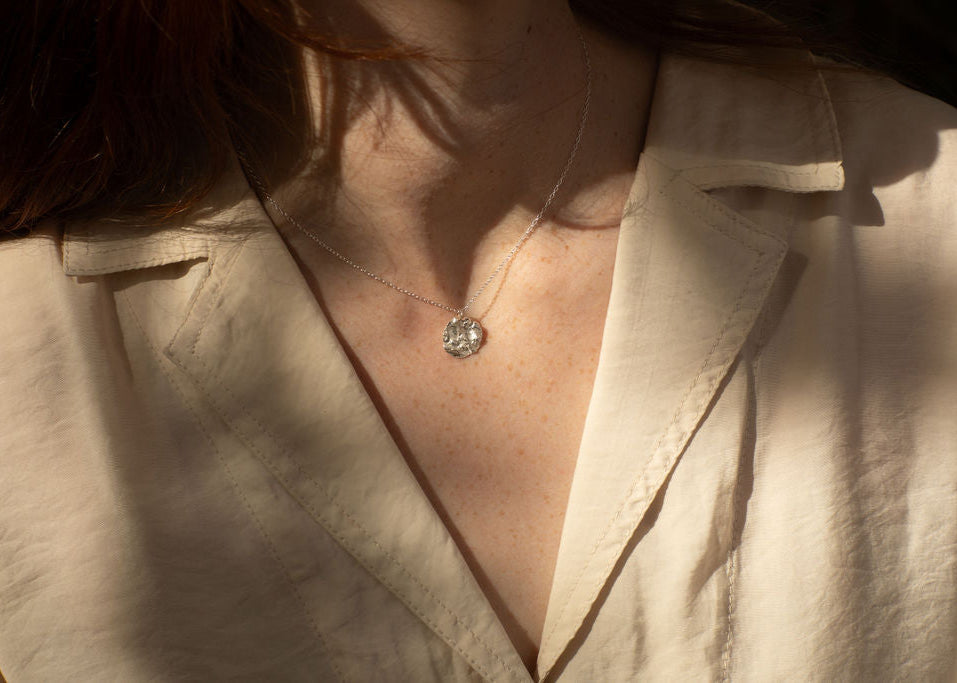 image of ladies torso wearing silver chain and textured pendant