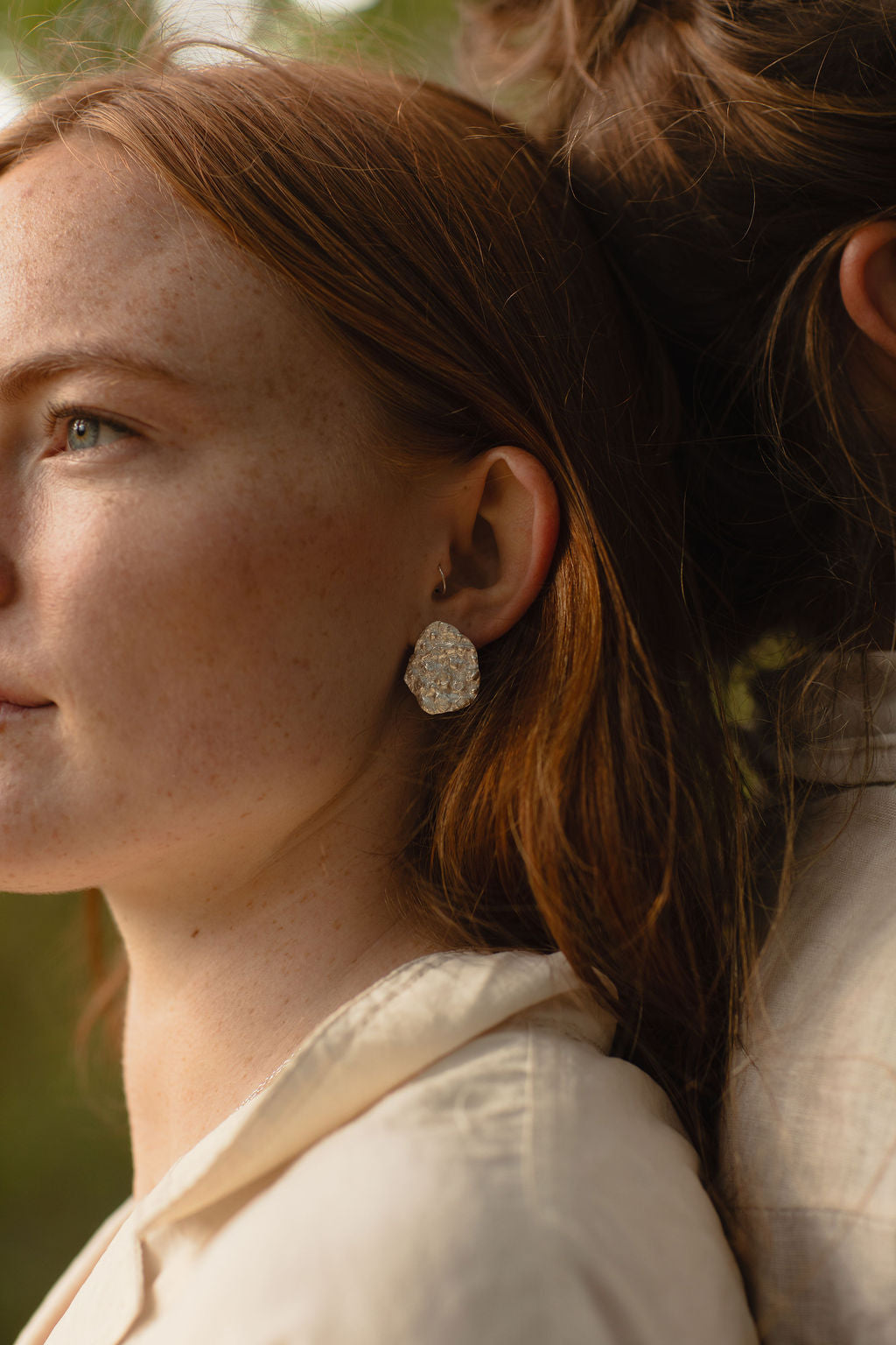 Close-up of a woman wearing a silver earring with a blurred background