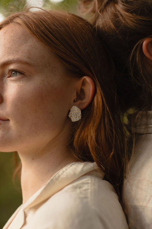 Close-up of a woman wearing a silver earring with a blurred background