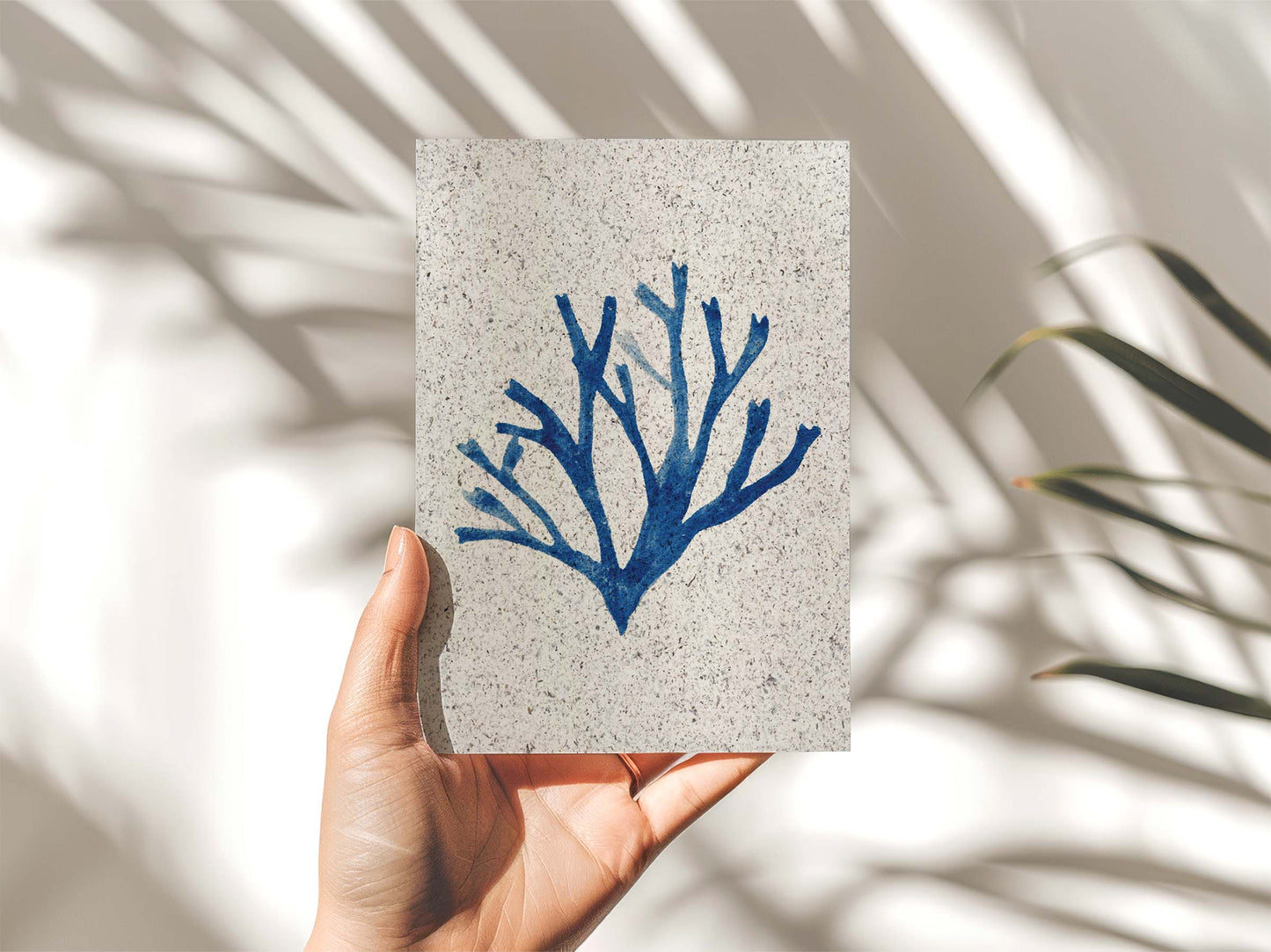 Hand holding a portrait painting Carageen seaweed, indigo coloured. On paper made from seaweed. From Kelpi Studio from Cornwall.