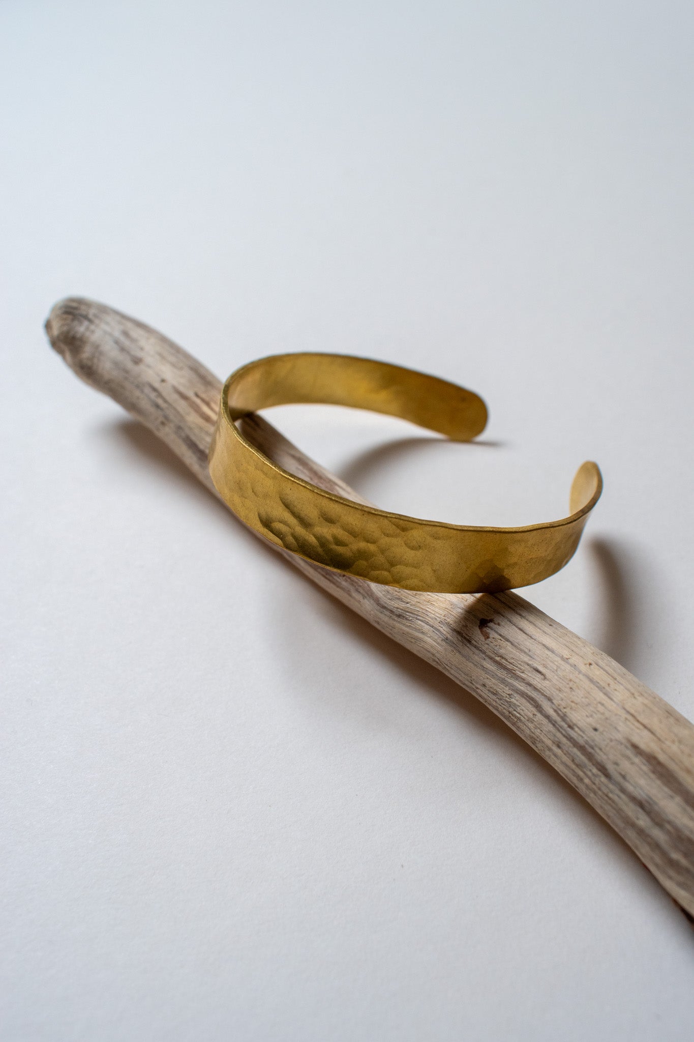 brass bracelet on a wooden stick against a white background