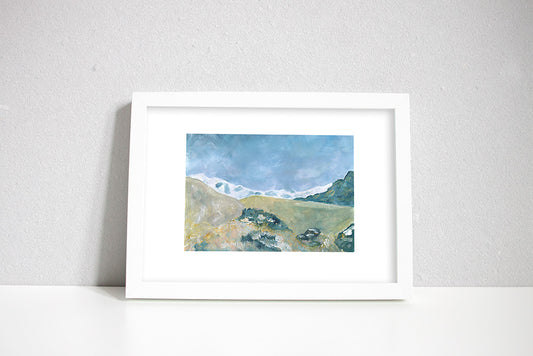 A framed painted picture of the Himalayan mountains, with a village in the foreground and white snow capped mountains in background.