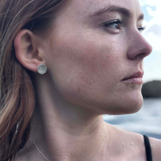 Woman with earring studs made from silver pendants