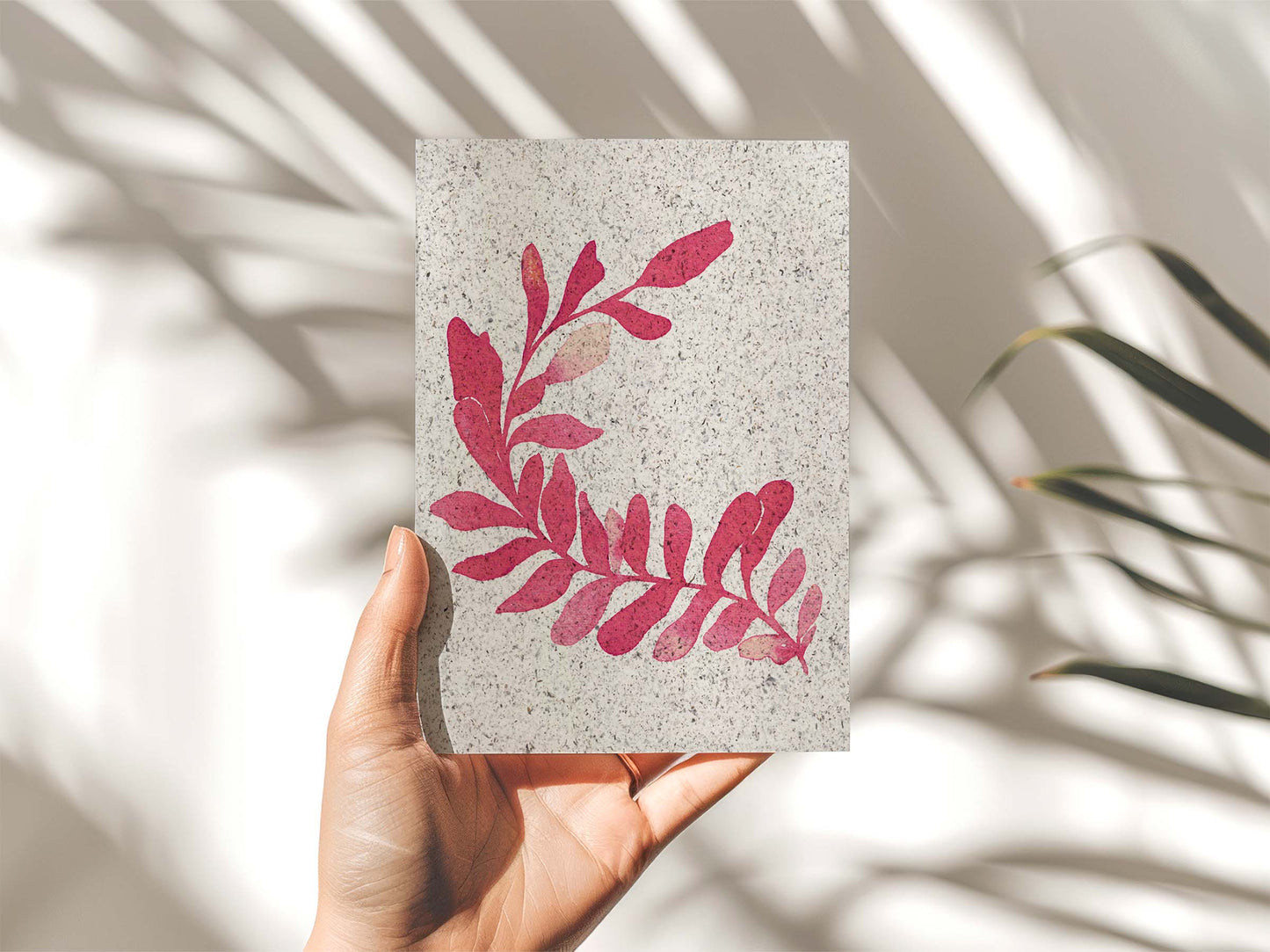 A hand holding a portrait painting of kelp, coral coloured. From Kelpi Studio in Cornwall.