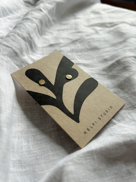 Brass studs on brown card on white fabric background