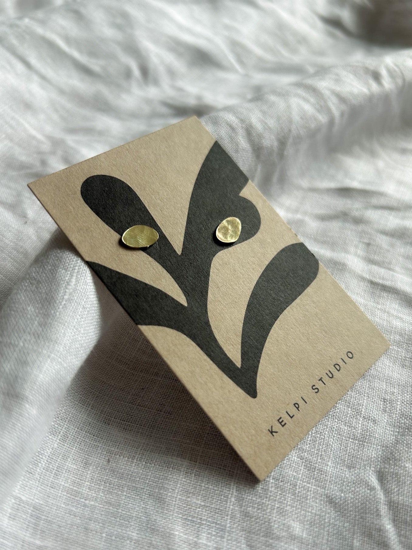 Brass studs on brown business card on cream fabric background