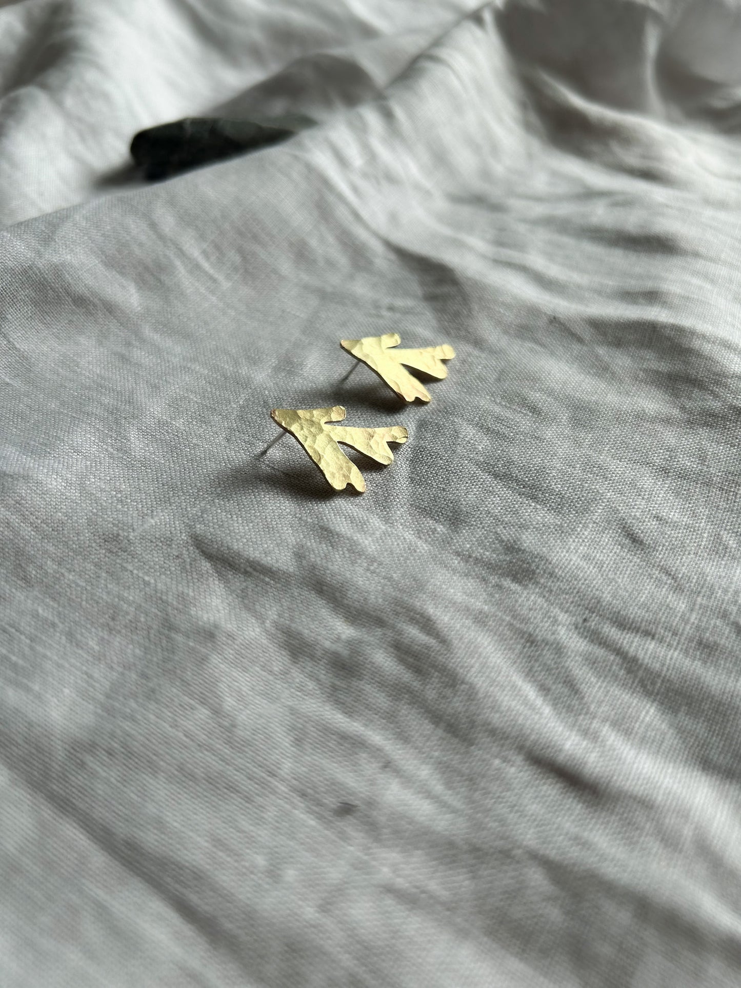 brass seaweed earrings on a cream fabric backgound