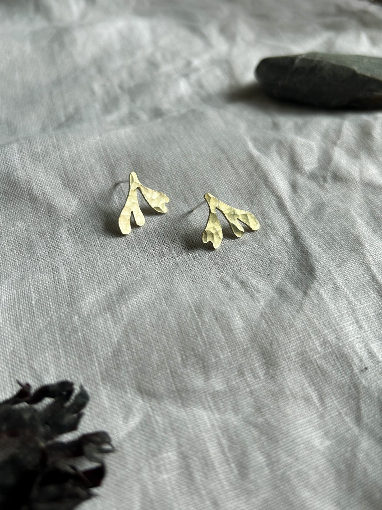 brass seaweed studs on cream linen background
