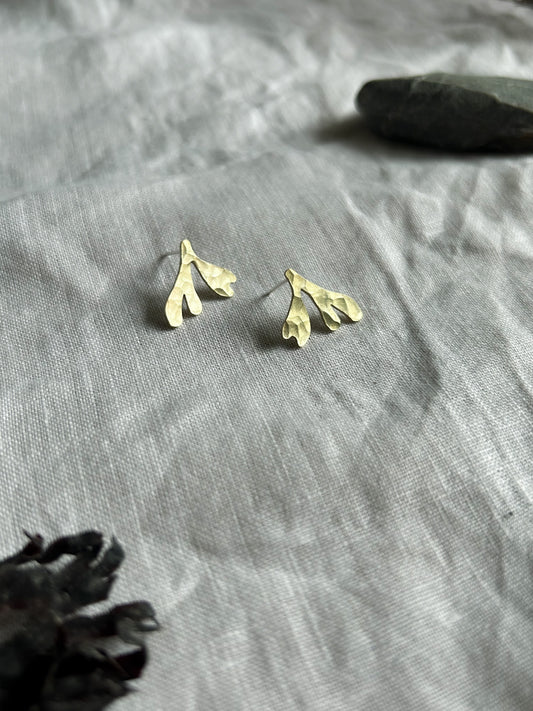 brass seaweed studs on cream linen background
