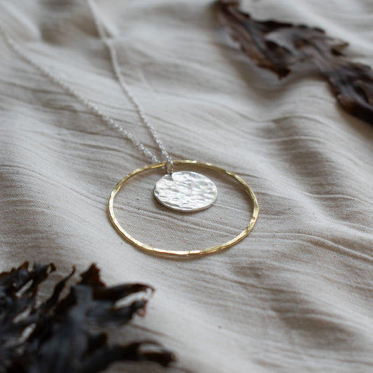 Necklace and pendant made from a brass hoop and a silver circle moon in the centre.