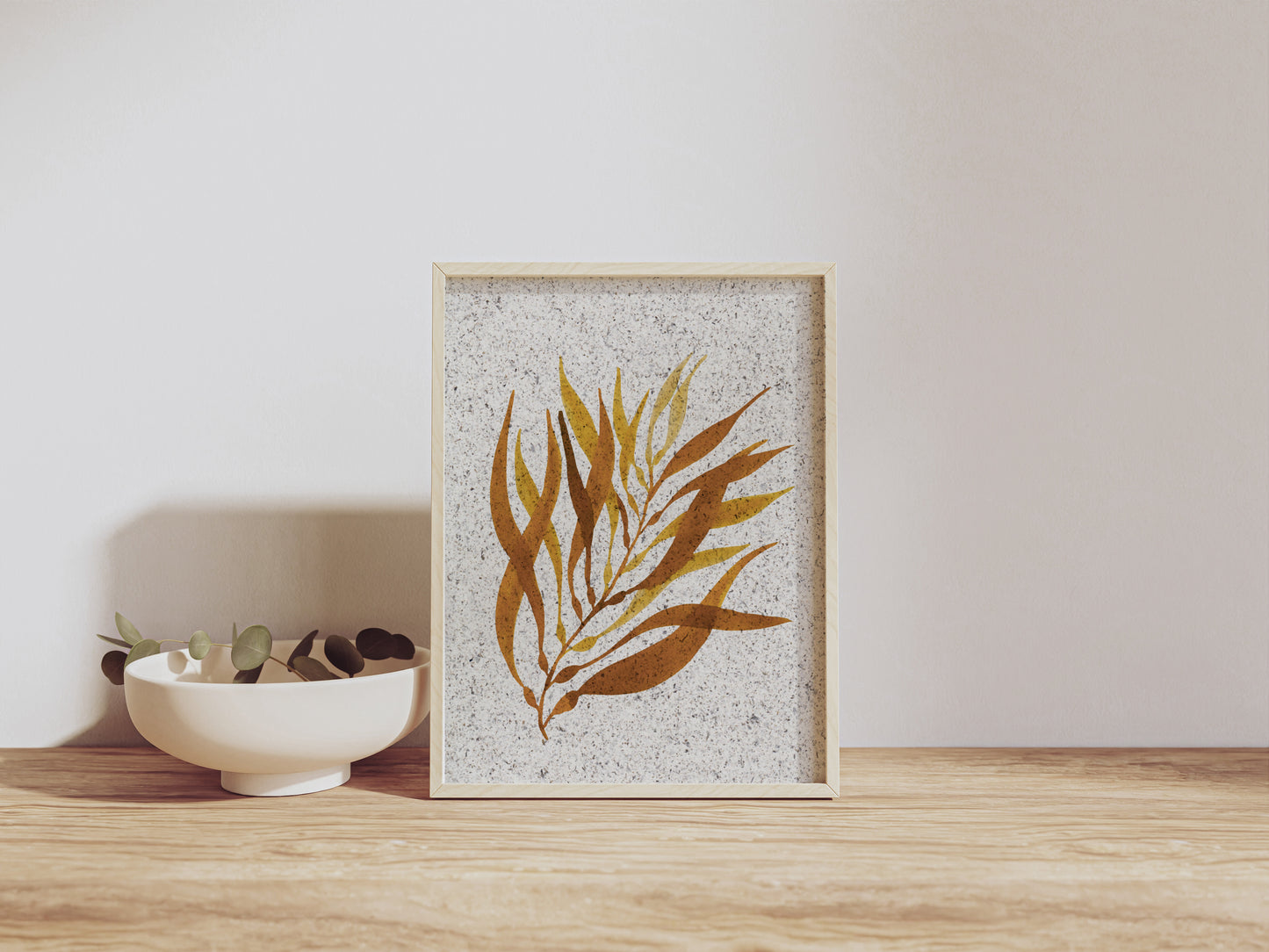 Framed artwork with a seaweed design on a wooden shelf