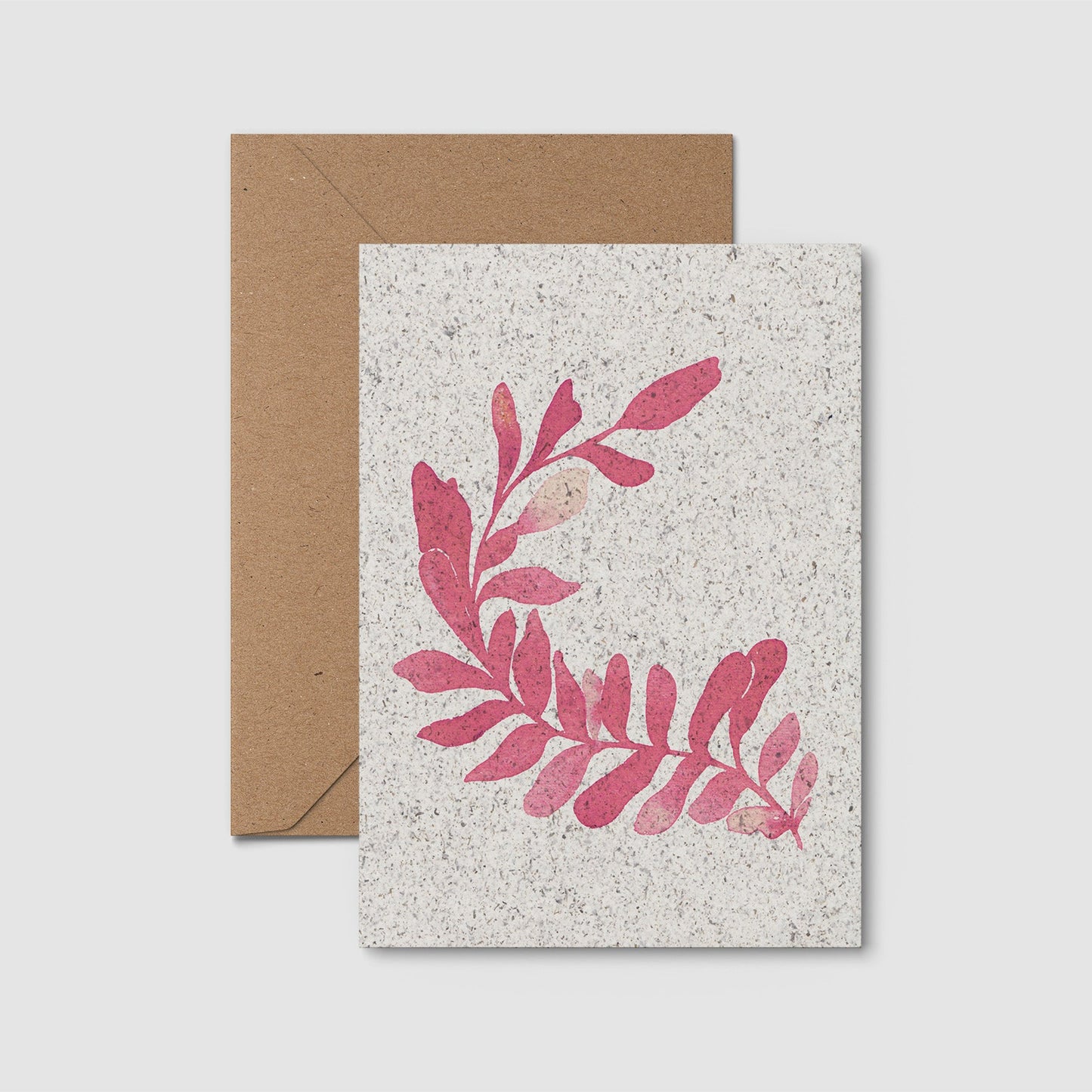 Greeting card with pink seaweed design on textured paper, accompanied by a brown envelope.