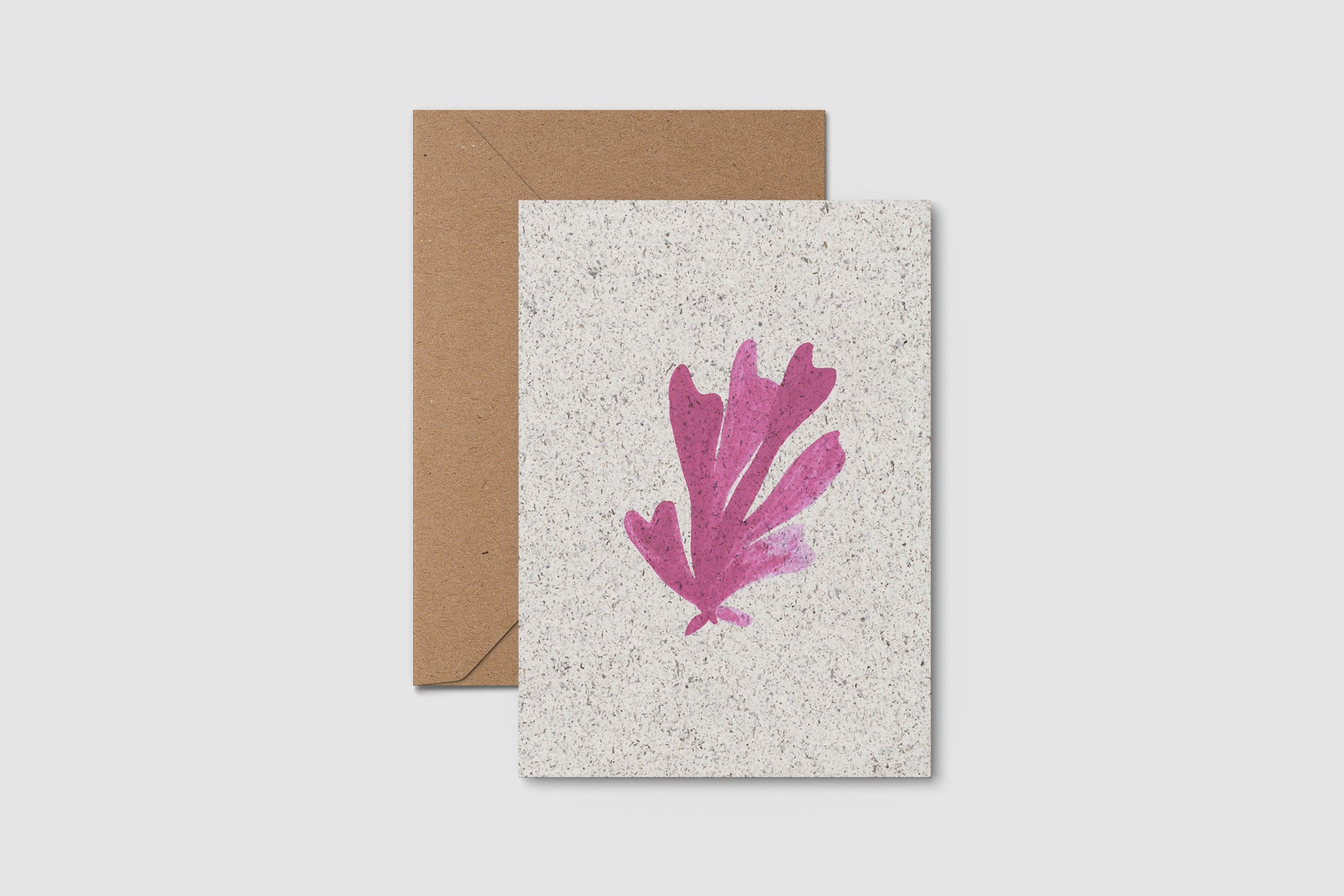 Card with pink leaf design and brown envelope on a light gray background