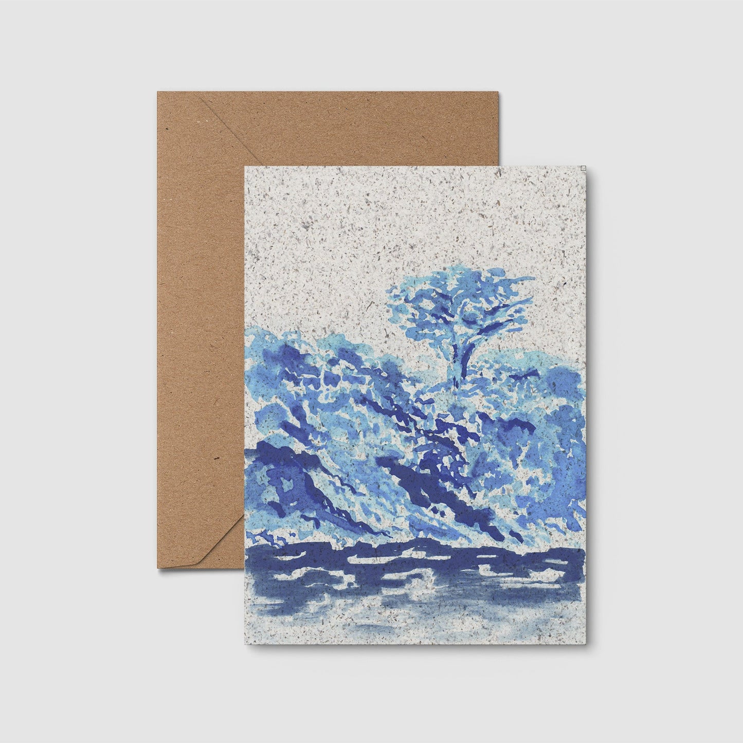 Greeting card with blue landscape design and brown envelope on a light gray background