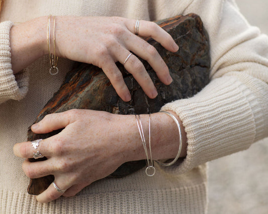 Person holding a rock with visible jewelry, wearing a beige sweater.