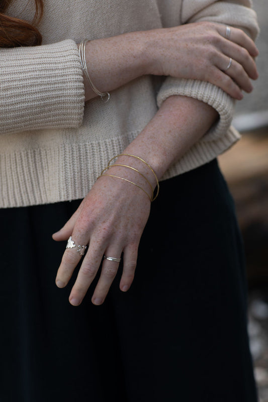 Close-up of a person wearing multiple rings and bracelets on a blurred background