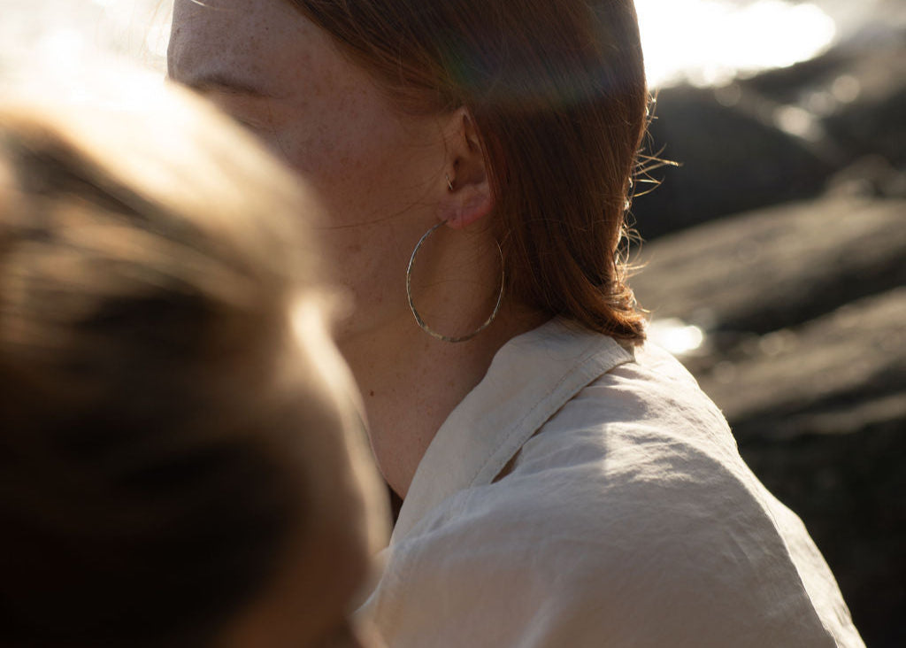 lady wearing silver hoops with blurred rocks in background