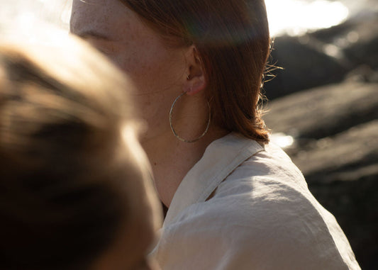 lady wearing silver hoops with blurred rocks in background