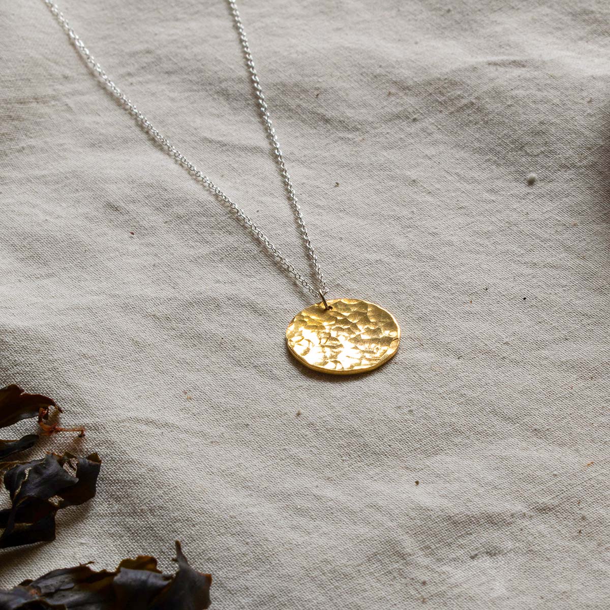 Necklace with a brass circular pendant that has been hammered