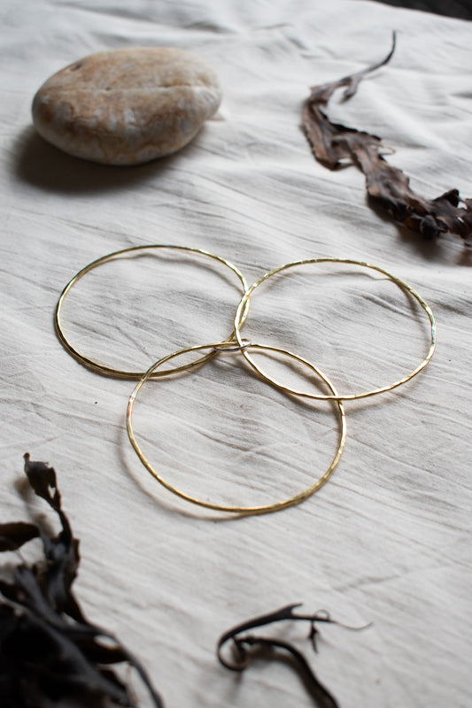 brass trio of bangles with silver loop on natural background