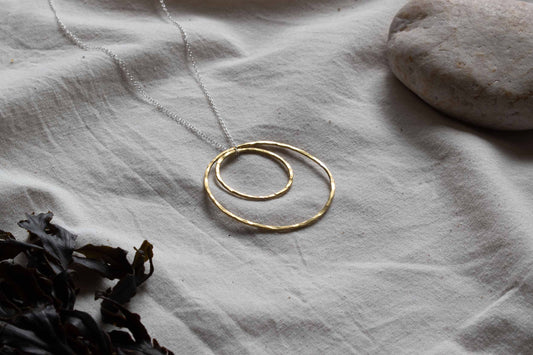 Necklace with a pendant made from two hammered brass hoops. 
