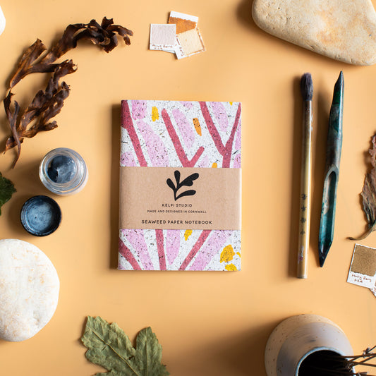 Seaweed notebook with a pink seaweed design on an artist's table