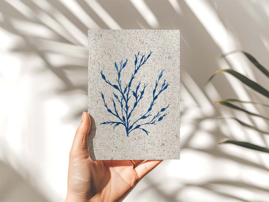 Hand holding a portrait painting Egg Wrack seaweed, indigo coloured. On paper made from seaweed. From Kelpi Studio in Cornwall. 
