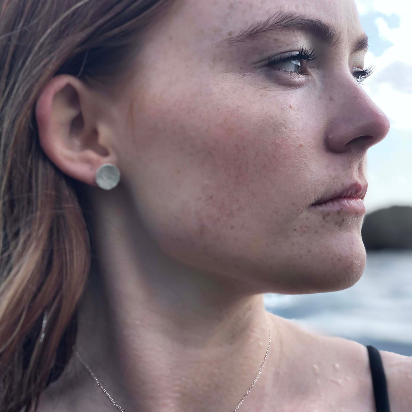Woman with earring studs made from silver pendants