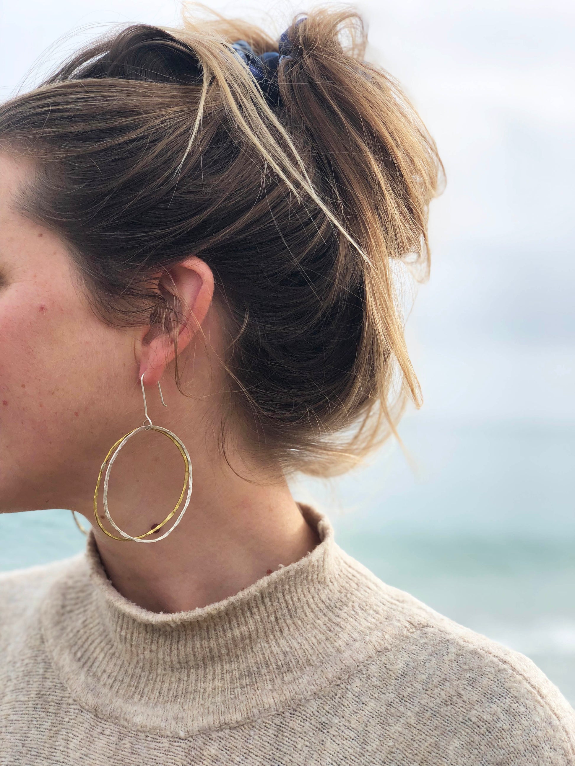 Person wearing gold hoop earrings with a blurred background