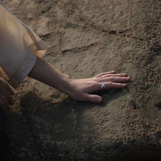 Hand on rock wearing seaweed shaped silver ring
