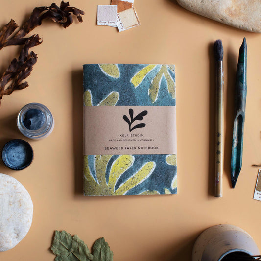 Seaweed notebook with a green kelp seaweed design on an artist's table