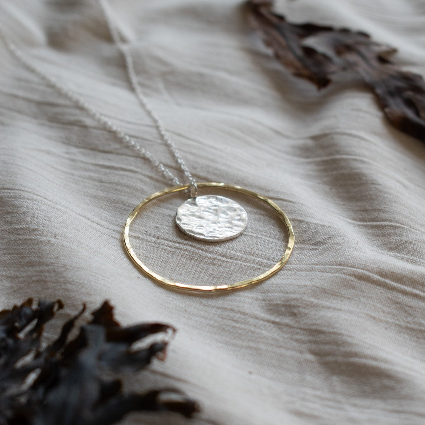 Necklace and pendant made from a brass hoop and a silver circle moon in the centre. 