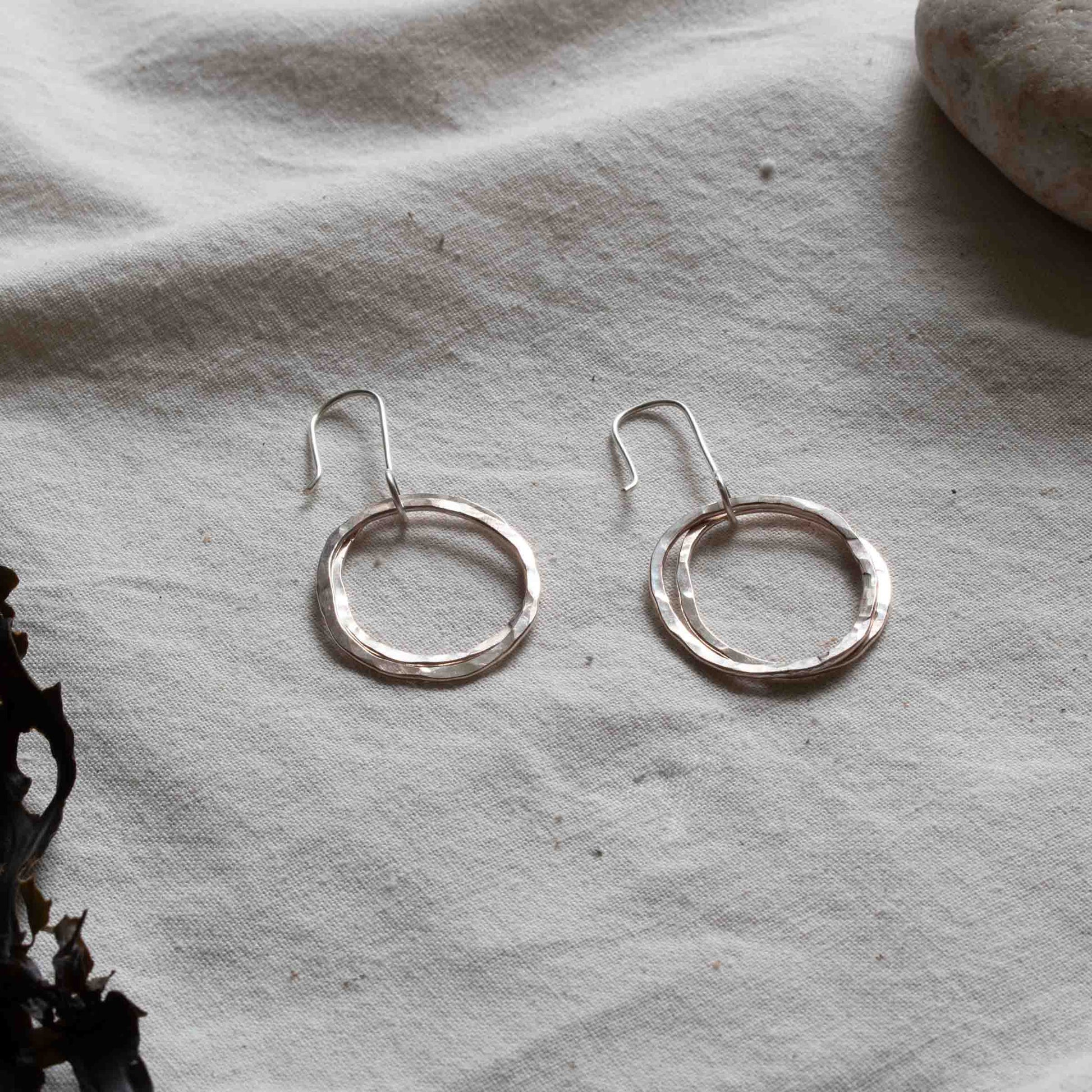 Two earrings made from hammered silver hoops. 